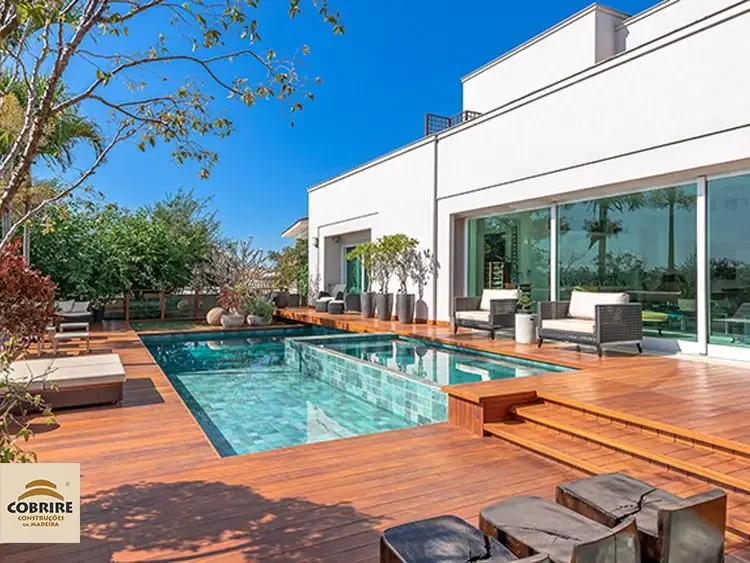 Piscina moderna com deck de madeira e área de lazer luxuosa.