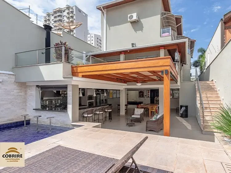 Design de pergolado de madeira para área de lazer: integração da varanda gourmet com piscina em residência de luxo.