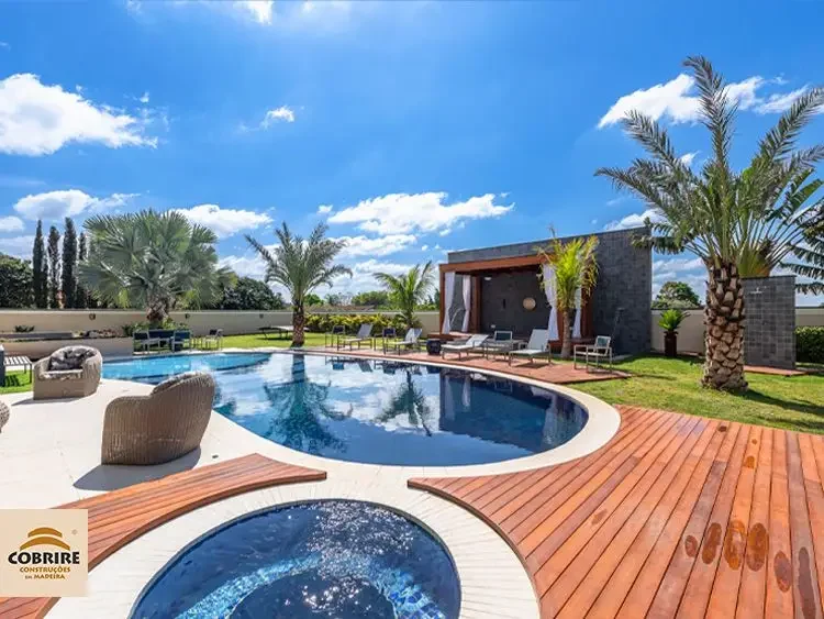 Área externa de luxo com piscina, deck e pergolado de madeira com forro de bambu e paisagismo | Cobrire Construções em Madeira
