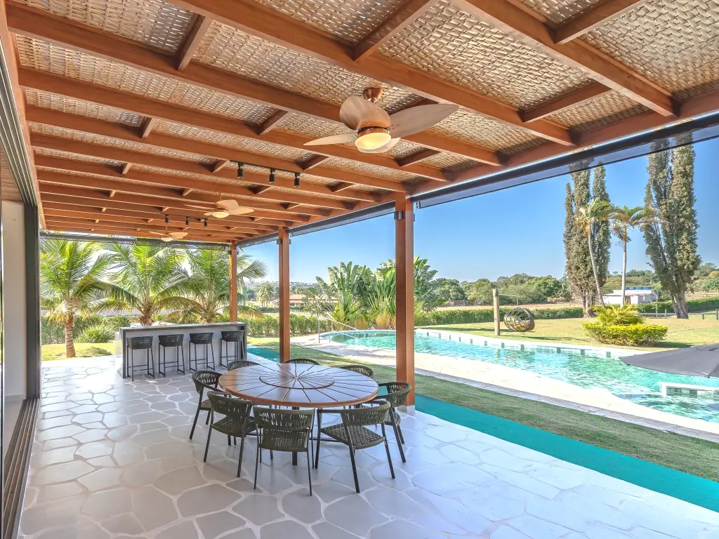 Pergolado em madeira com forro de bambu natural junto à piscina.