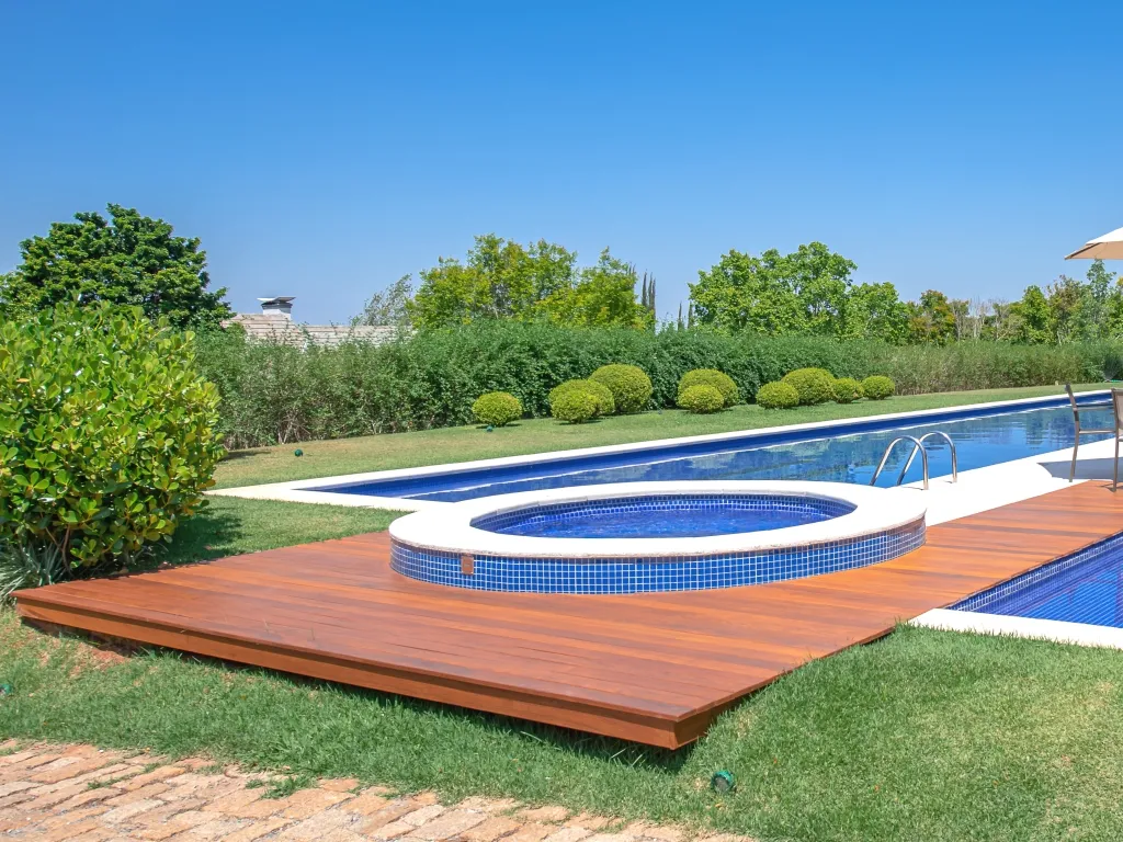 Área de lazer com deck em madeira integrado à piscina e paisagismo.